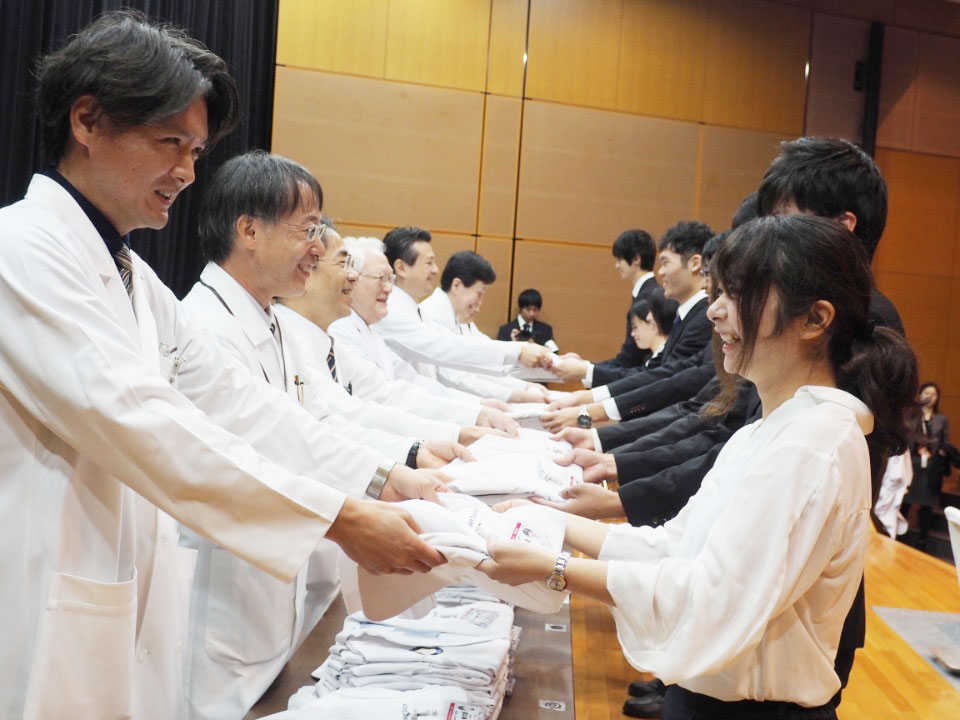 列席者から学生１人１人に白衣が手渡された。