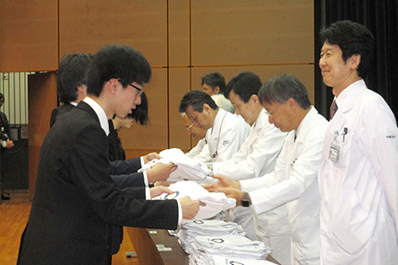 列席者から学生１人１人に白衣が手渡された。